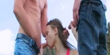 Nasty 18yo chick sucking two huge cock outdoors