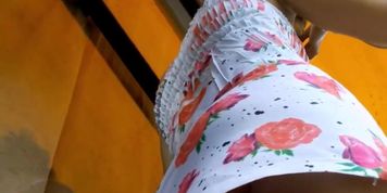 An inquiring camera looks under a white dress with rose print