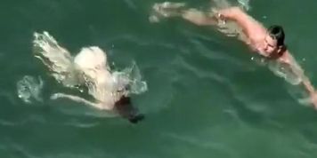 Nudist redhead swimming in the water