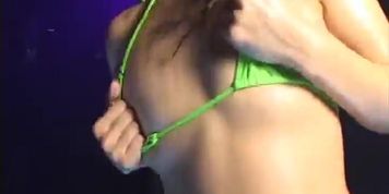 Microbikini-clad tight-bodied oiled asian girl dances in a club