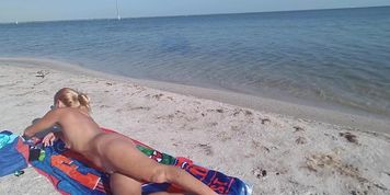 Nude mature blonde tanning on the beach
