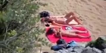 Two nude girls sun bathing on beach.