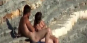 Nudist couple by a rocky seashore