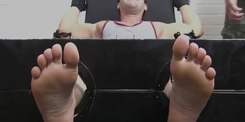 Muscly stud restrained for erotic torment and foot tickling