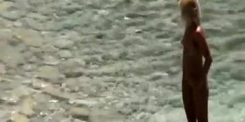 Blonde nudist woman enters the water
