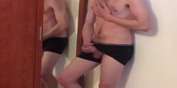 Blonde boy loses his clothes in front of a mirror