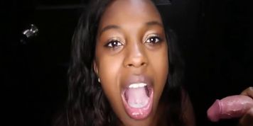 A sexy black girl gives a blowjob to a white guy in a gloryhole booth